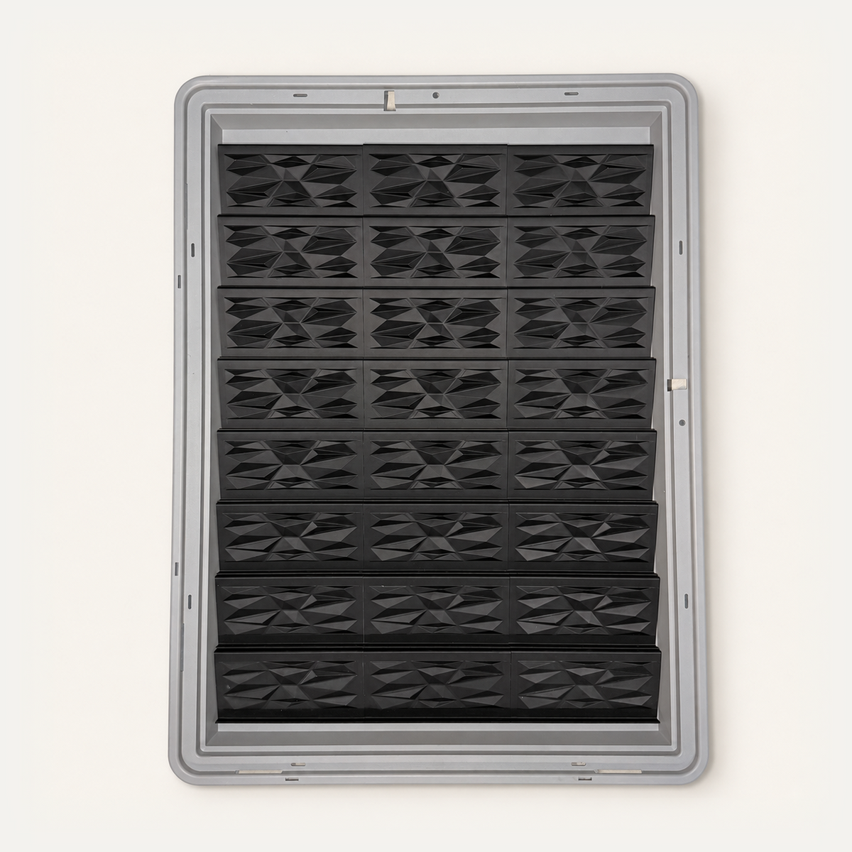 Top-down view of 24 black faceted risers in three columns inside a gray Zion display case